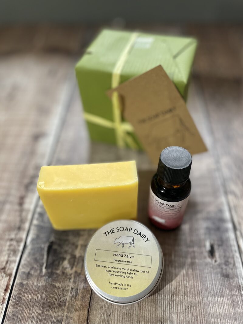 Skincare gift set of soap, hand salve and face oil with a gift box on a wooden board