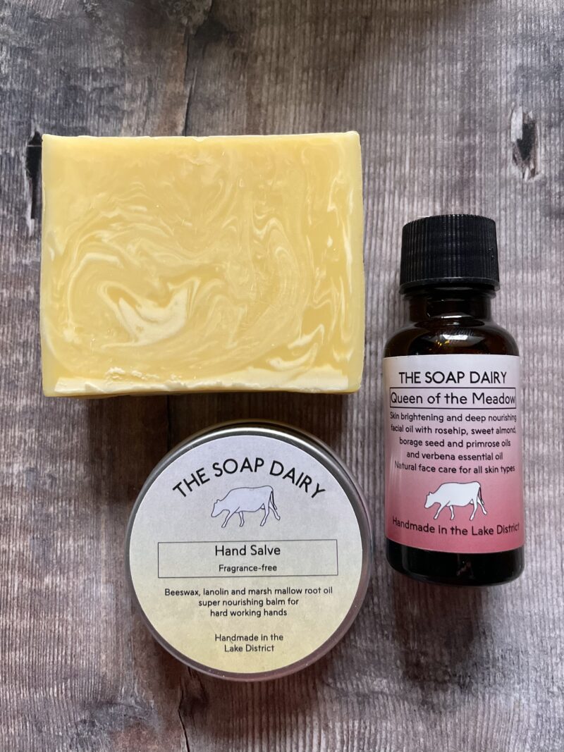 Skincare gift set of soap, hand salve and face oil on a wooden board